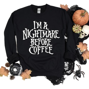 Peut inclure: Sweat-shirt noir avec un texte blanc qui dit "I'm a nightmare before coffee". Le sweat-shirt est entour&eacute; de d&eacute;corations d'Halloween, notamment des citrouilles, un cr&acirc;ne et des toiles d'araign&eacute;es.
