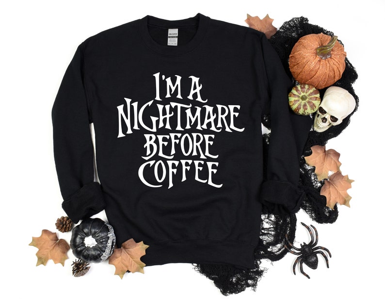 Peut inclure: Sweat-shirt noir avec un texte blanc qui dit "I'm a nightmare before coffee". Le sweat-shirt est entour&eacute; de d&eacute;corations d'Halloween, notamment des citrouilles, un cr&acirc;ne et des toiles d'araign&eacute;es.