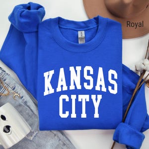 May include: Royal blue long-sleeved sweatshirt with white text that reads "Kansas City".