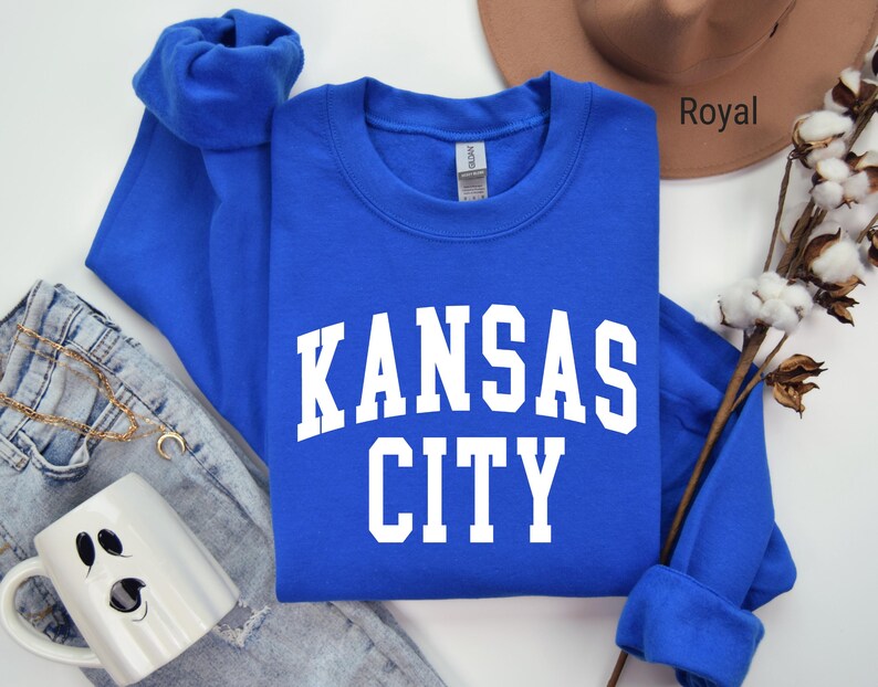 May include: Royal blue long-sleeved sweatshirt with white text that reads "Kansas City".