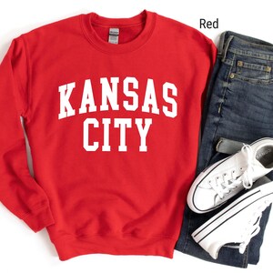 May include: Red sweatshirt with white text that reads "KANSAS CITY".