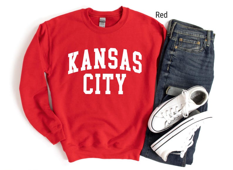 May include: Red sweatshirt with white text that reads "KANSAS CITY".
