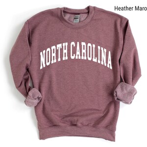 Pode incluir: Uma camisa de moletom marrom com o texto "NORTH CAROLINA" impresso em branco.