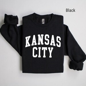 May include: Black long-sleeved sweatshirt with white text that reads "KANSAS CITY".
