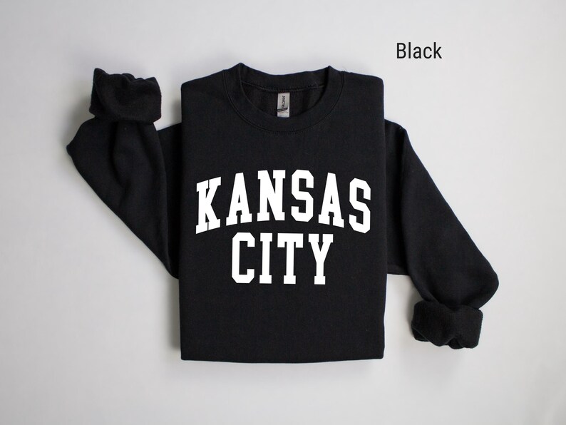 May include: Black long-sleeved sweatshirt with white text that reads "KANSAS CITY".