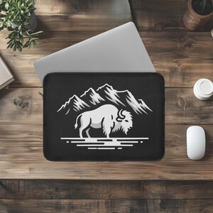 May include: Black laptop sleeve with a white silhouette of a buffalo standing in front of a mountain range.