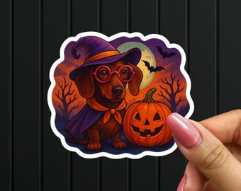 May include: A sticker featuring a dachshund dressed as a witch for Halloween. The dog wears a purple witch hat, cape, and glasses, with an orange scarf. A carved pumpkin and full moon are in the background.