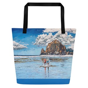 Può includere: Una borsa tote con una stampa di una scena di spiaggia, che mostra una grande formazione rocciosa, mare blu e un cielo nuvoloso. La borsa ha manici neri e una base blu. L'opera d'arte raffigura due persone in acqua.