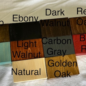 May include: Wood stain colour samples in various shades of brown, red, grey, and black. The samples are labelled with names like "Jacob ean", "Ebony", "Dark Walnut", "Red Oak", "Light Walnut", "Carbon Grey", "Barn Red", "Aqua", "Natural", and "Golden Oak".