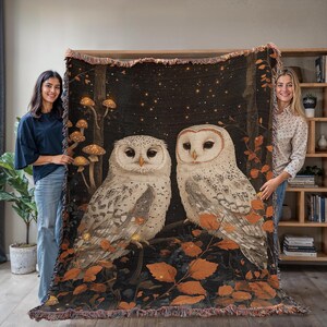Magical woodland cottagecore throw blanket with two white owls among glowing mushrooms and autumn leaves on dark starry background, cotton woven tapestry with fringe