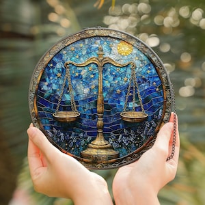 May include: A round stained glass window depicting a gold scale design against a blue and gold background. The scale is surrounded by a blue and gold mosaic pattern with stars and a sun. The window is suspended from a black chain.