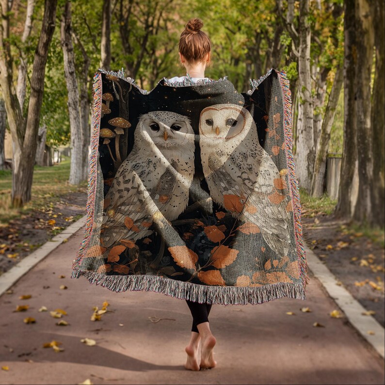 Cotton woven throw blanket displaying snowy owl pair in mystical nighttime forest scene with autumn foliage, mushrooms and twinkling stars