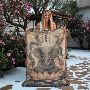 May include: A tapestry throw blanket featuring a gray elephant sitting in a lotus position with Japanese text that reads "智慧の象" which translates to "Elephant of Wisdom".