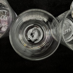 May include: Three clear glass tumblers with etched designs. The center tumbler has the words "Go Birds!" etched on the bottom. The tumbler on the left has the words "Go Birds!" etched on the bottom. The tumbler on the right has the words "Go Birds!" etched on the bottom.