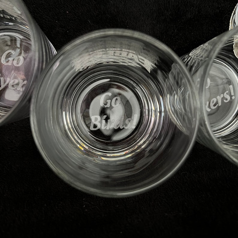 May include: Three clear glass tumblers with etched designs. The center tumbler has the words "Go Birds!" etched on the bottom. The tumbler on the left has the words "Go Birds!" etched on the bottom. The tumbler on the right has the words "Go Birds!" etched on the bottom.