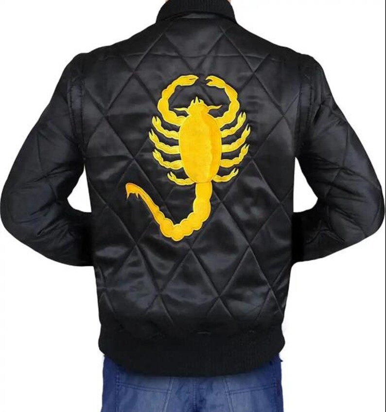 K&ouml;nnte beinhalten: Schwarze, gesteppte Bomberjacke mit gelbem Skorpion-Emblem auf dem R&uuml;cken. Die Jacke hat einen gerippten Kragen und B&uuml;ndchen. Das Skorpion-Design ist detailliert und mittig auf dem R&uuml;cken der Jacke platziert.