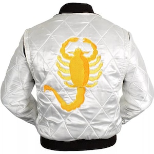 Könnte beinhalten: Weiße Satin-Bomberjacke mit Steppmuster und schwarzem geripptem Kragen und Bündchen. Auf der Rückseite befindet sich ein großes, gesticktes gelbes Skorpion-Design. Die Jacke hat eine klassische Bomber-Silhouette.