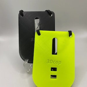 Puede incluir: Dos fundas para teléfono con un cordón. Una es negra y la otra es de color amarillo brillante. La funda amarilla tiene el texto "3DCop" impreso.