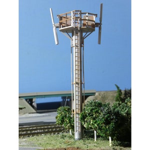 Könnte beinhalten: Ein Modell eines hohen, weißen, hölzernen Turms mit einer Leiter und einer Plattform oben. Der Turm hat vier weiße, hölzerne Flügel, die an der Plattform befestigt sind und an eine Windmühle erinnern.