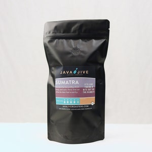 May include: A black coffee bag with a label that reads "SUMATRA" from Java Jive Coffee Company. The label also includes the text "It's like taking a bite out of the planet!" and "JAVAJIVEROASTERS.COM".