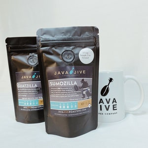 May include: Two black coffee bags labeled "Guatzilla" and "Sumozilla" with a white mug. The mug has the "Java Jive Coffee Company" logo. The coffee bags have a sample size of 2 oz.