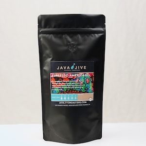 May include: Black coffee bag with a label that reads "Espresso Americano" from Java Jive Coffee Company. The label features colorful artwork and text describing the coffee's origin and flavor profile. The bag has a round vent and a zip closure.