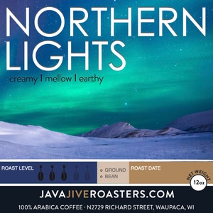 May include: A coffee bag with the words "NORTHERN LIGHTS" in white, over a landscape of snow-covered mountains and a green and blue aurora borealis. The bag also includes the text "creamy I mellow I earthy" and the net weight of 12oz.