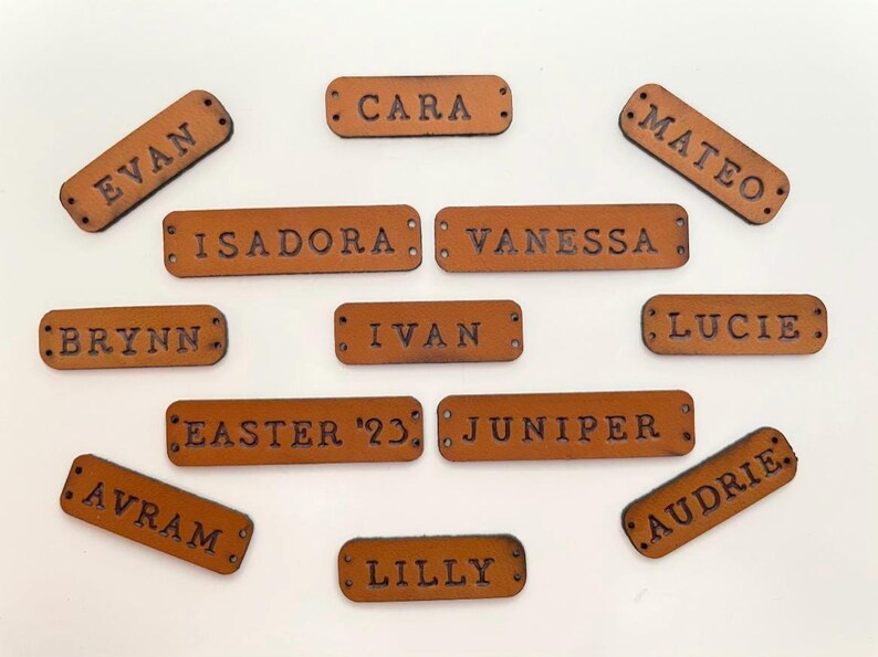 Custom leather name tags with various names displayed on a light background.