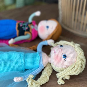 Handmade crocheted amigurumi dolls of Elsa and Anna, inspired by Frozen. Detailed with colorful outfits, perfect for custom name personalization or gifting.