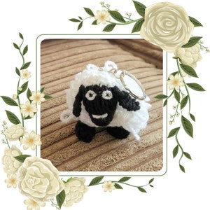 May include: A white and black crocheted sheep keychain with a silver key ring. The sheep has a black face and a white body.