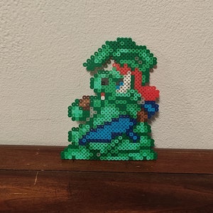 Könnte beinhalten: Eine grüne Pixel-Art-Figur eines Videospielcharakters. Die Figur trägt einen grünen Hut und eine blaue Hose. Die Figur hält ein braunes Objekt in ihrer rechten Hand.