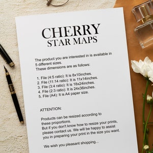 May include: A white sheet of paper with black text describing the different sizes available for a Cherry Star Map. The text includes the dimensions in inches and the aspect ratio of each size. The paper is on a brown surface with a pair of glasses and a bottle of perfume.