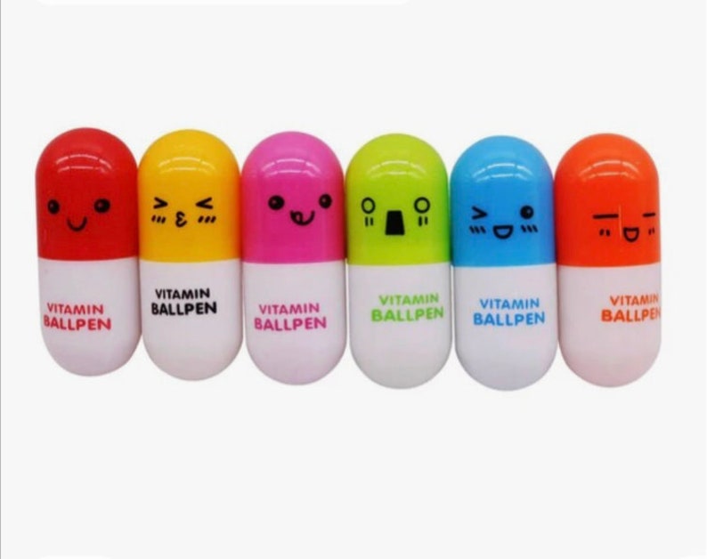 May include: Six colorful ballpoint pens shaped like vitamin capsules with different cartoon faces. Each pen has the text "VITAMIN BALLPEN" printed on the bottom.