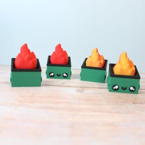 May include: Four miniature green dumpster figurines with black tops, each containing a flame-shaped object in red and yellow. The dumpsters have smiling faces. The background is a light blue.