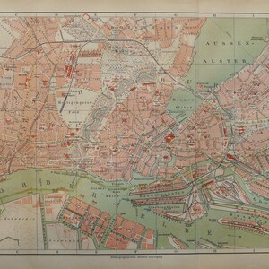Op de afbeelding: Een vintage kaart van Hamburg en Altona, Duitsland, die de indeling van de stad en belangrijke bezienswaardigheden laat zien. De kaart is gedrukt in tinten groen, bruin en rood, met tekst in het Duits.