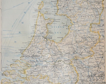 May include: A vintage map of the Netherlands, showing the country's major cities, rivers, and canals. The map is printed in black and white with blue and yellow accents. The map includes the text "NIEDERLANDE" in the top left corner.