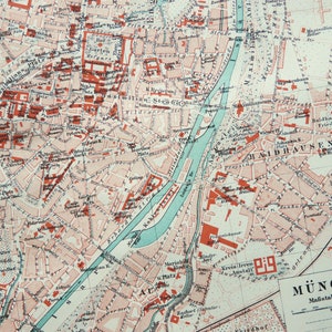May include: A detailed vintage map of Munich, Germany, featuring a network of streets, buildings, and a river. The map uses a color scheme of red, white, and blue, with text labels in German. The scale is 1:20000.