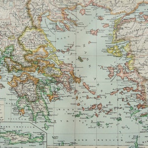 May include: A detailed vintage map of Greece, showing geographical features and regions. The map uses various colours to differentiate areas and includes text labels for cities, islands, and seas. Printed on aged paper, it has a classic aesthetic.