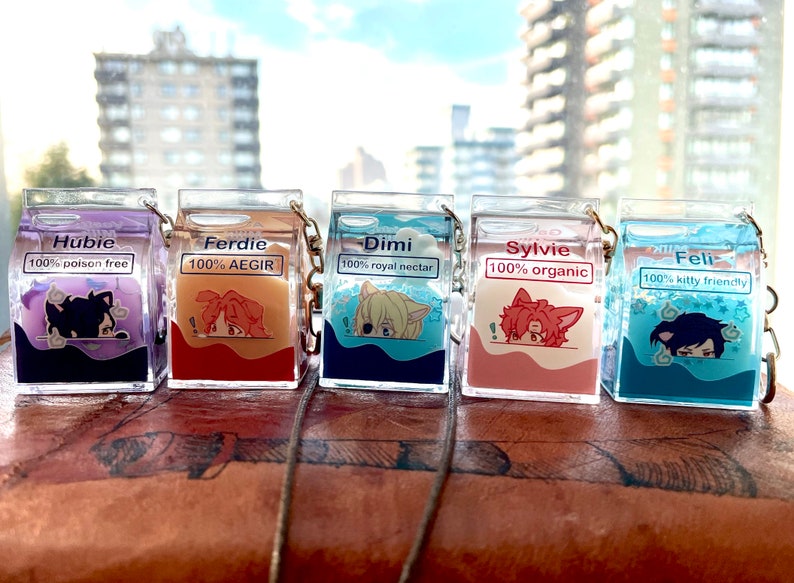 May include: Five colorful milk carton-shaped keychains with different character illustrations and names. The keychains are made of clear plastic with glitter inside. The characters are Hubie, Ferdie, Dimi, Sylvie, and Feli.