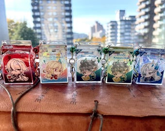 May include: Five clear acrylic keychains with anime-style character illustrations. Each keychain is shaped like a small carton and features a different design and text: "Orphan Tears," "Mourning Flower Extract," and "Divine Knowledge" twice, and "Hydro Dragon Tears."