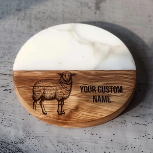 May include: A round wooden coaster with a white epoxy top. The coaster features a laser-engraved image of a sheep and the text "YOUR CUSTOM NAME".