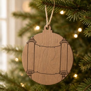 May include: A wooden Christmas ornament with a scroll design. The ornament is round with a light brown finish and a black scroll design. It hangs from a natural twine string. The ornament is hanging on a Christmas tree.