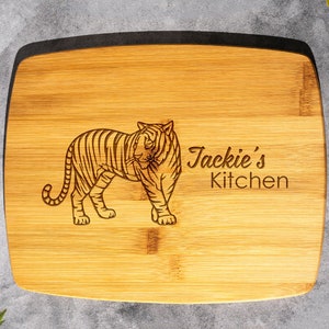 Op de afbeelding: Een rechthoekig bamboe snijplank met een zwarte rand. De plank is gegraveerd met een tijgerillustratie en de tekst "Jackie's Kitchen".