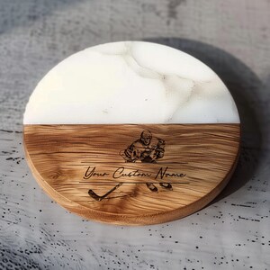 May include: A round wooden coaster with a white epoxy top. The coaster has a woodburned image of a hockey player and the text "Your Custom Name".