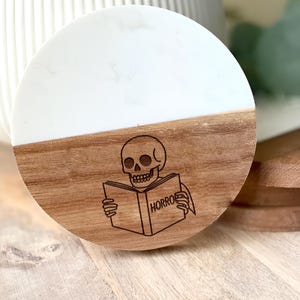 Spooky Horror Book Coaster: Skull, Candle, and Open Book Illustration