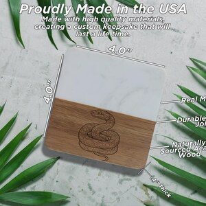a marble coaster with a snake design, surrounded by green leaves.