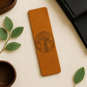 May include: A tan leather bookmark with rounded corners. A circular design in the center features a brain, spinal cord, and neuron illustration. The bookmark is approximately 7 inches long.