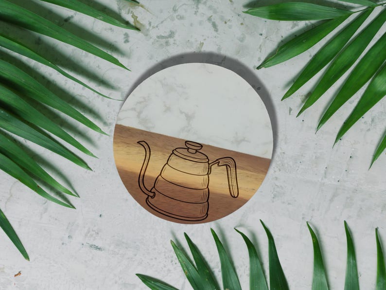 A white circular plate with a black and white illustration of a coffee pot is surrounded by green leaves on a white background.