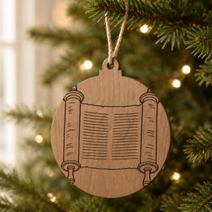 May include: A round wooden Christmas ornament with a scroll design. The ornament is made of light brown wood and has a detailed engraving of a scroll with text. It hangs from a natural twine string, perfect for holiday decor.