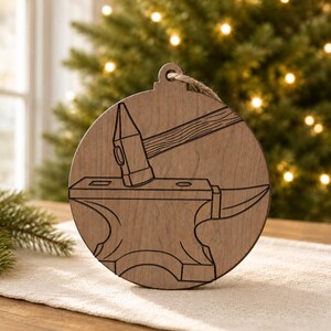May include: A round, wooden Christmas ornament with a blacksmith theme. The ornament features a hammer striking an anvil, with a jute string for hanging. The design is etched into the wood, creating a rustic, handcrafted look.